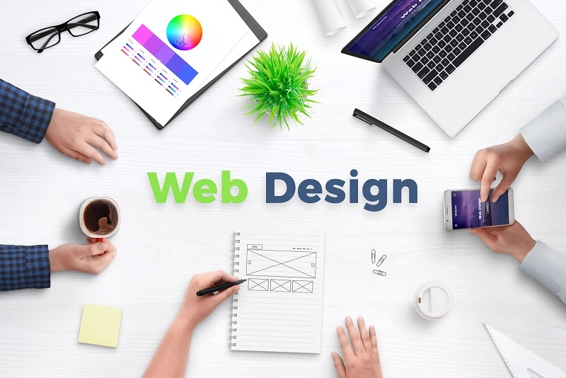 website-design-services-image-of-people-around-table-with-web-design-tools